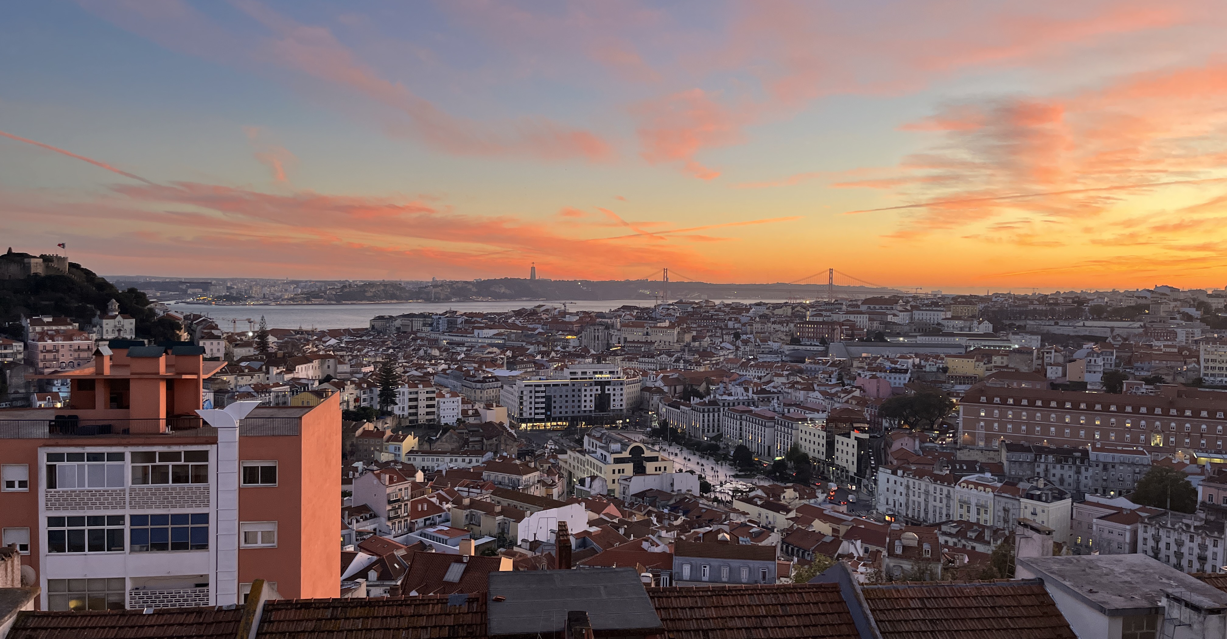 Lisbon skyline at sunset with the 25 de Abril bridge and Cristo Rei on the horizon
